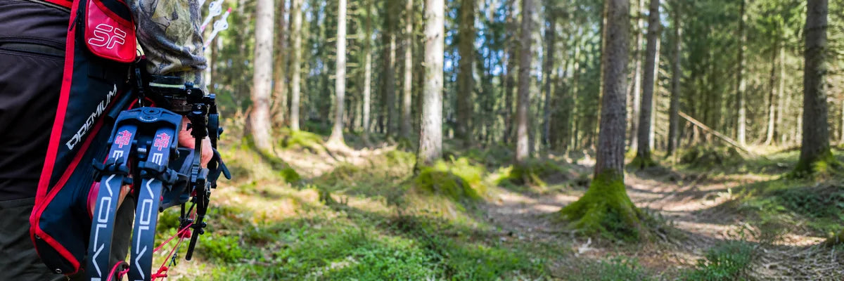 Bueskytter med PSE Evolve compoundbue og rødt pilkogger i skogen